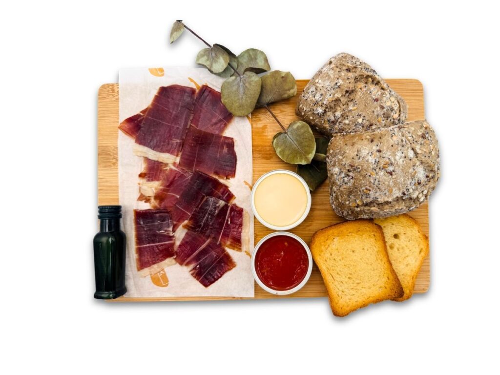 Desayuno salado añadiendo a tu cesta o caja jamón ibérico de cebo, panecillos, aceite AOVE, queso untable y tomate triturado. Un desayuno de lo más mediterráneo